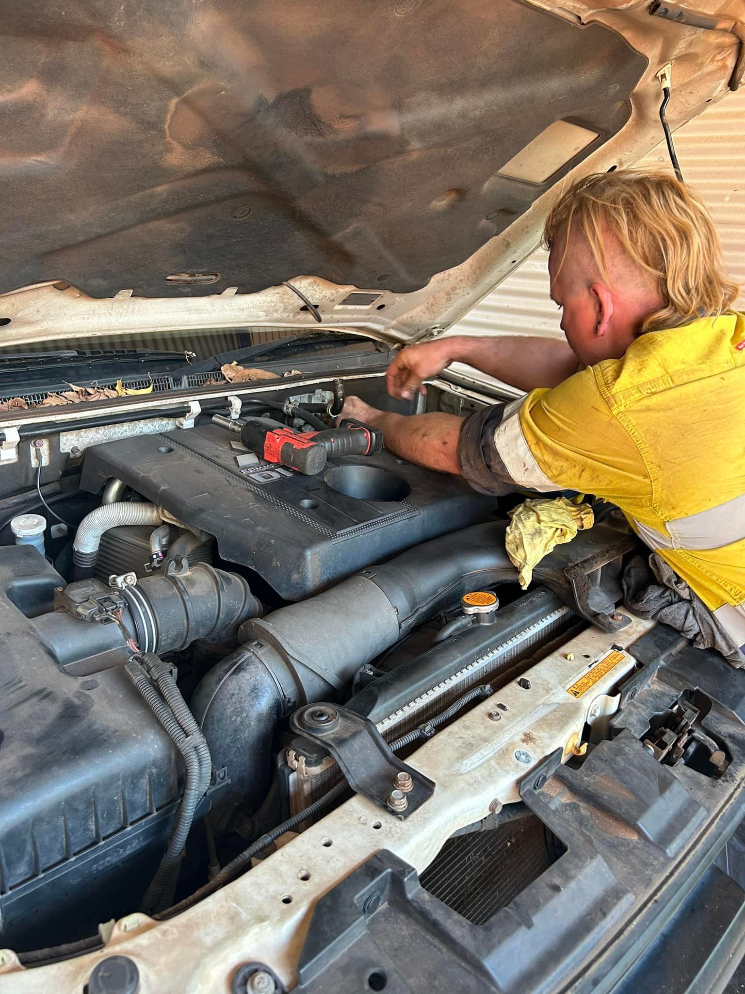 Person Changing a Flat Tire on a Red Car, Outdoors — Mudpig Mechanical In Humpty Doo, NT