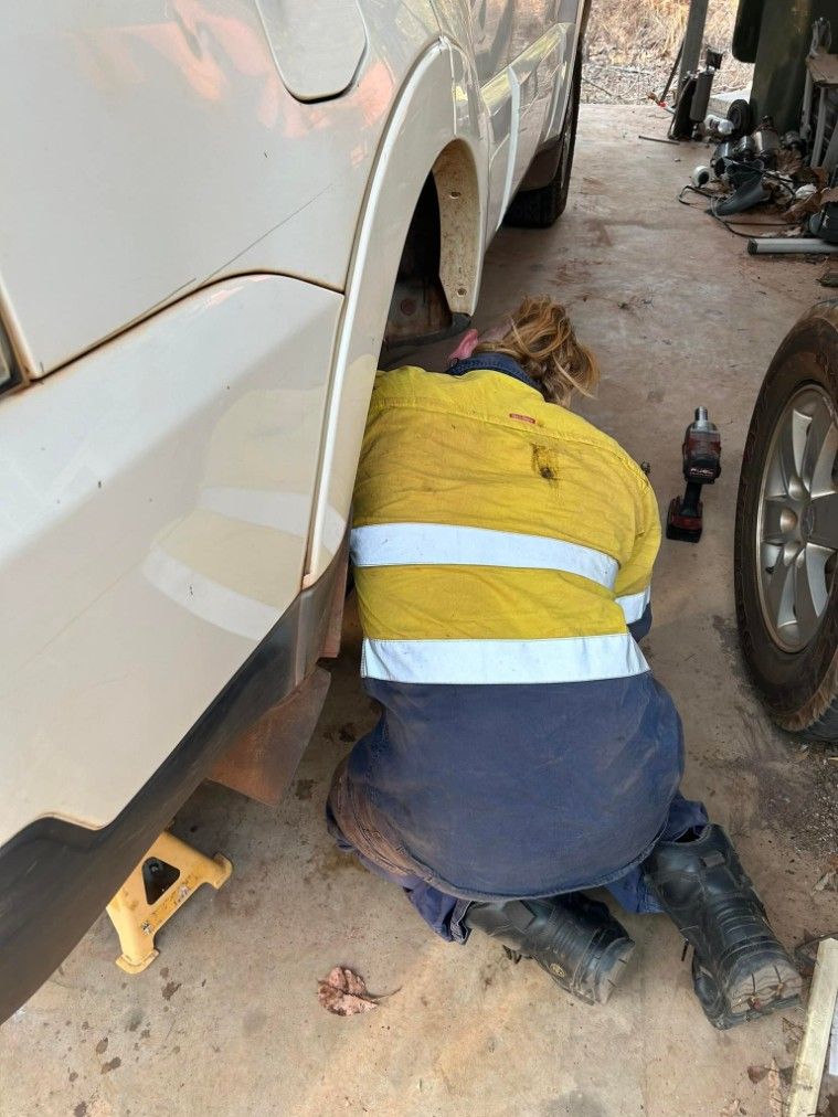 Person in Workwear Crouched Under a White Vehicle — Mudpig Mechanical In Humpty Doo, NT