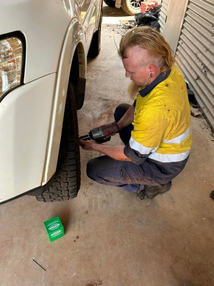 Man With Blonde Mullet Uses Power Tool on a Car Tire in a Garage — Mudpig Mechanical In Humpty Doo, NT