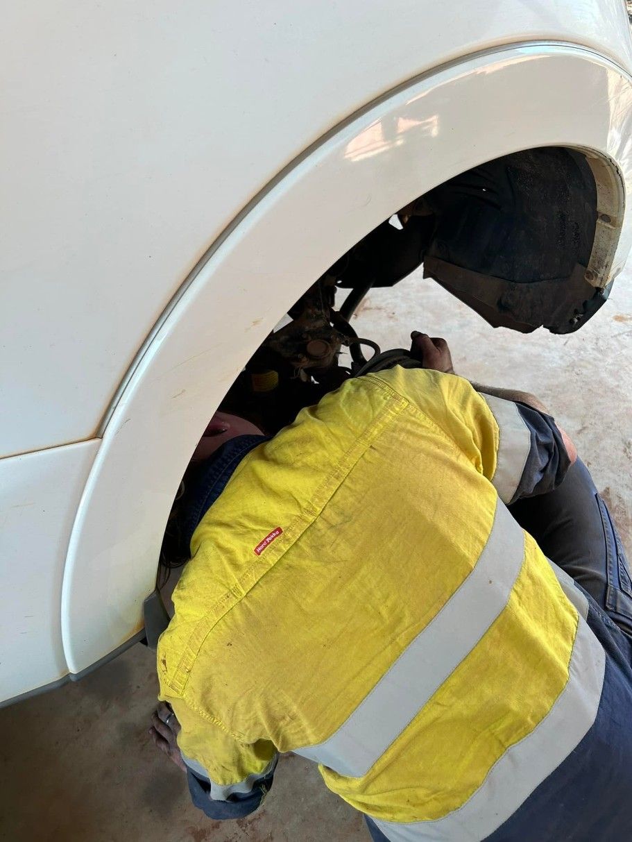 Mechanic in Yellow Safety Gear Working on a Car's Wheel — Mudpig Mechanical In Humpty Doo, NT