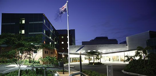 A flag is flying in front of a large building at night.