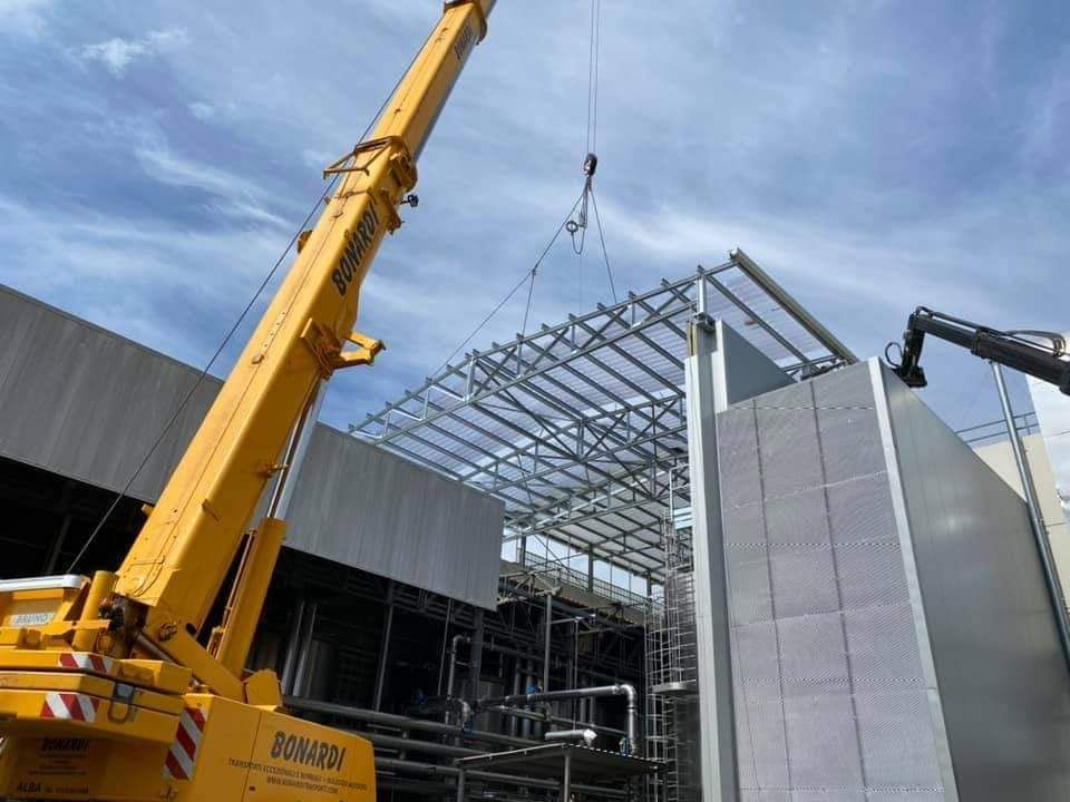 Autogru che sta sollevando copertura edificio in costruzione