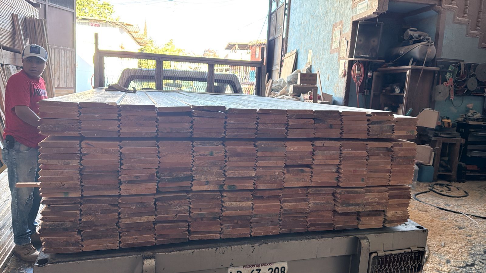 Un hombre está de pie junto a una pila de madera.