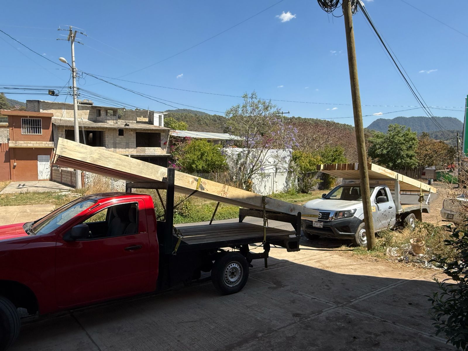 Un camión rojo está estacionado al lado de un camión blanco.