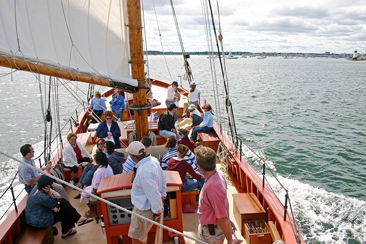 A group of people are sitting on the deck of a sailboat in the water.