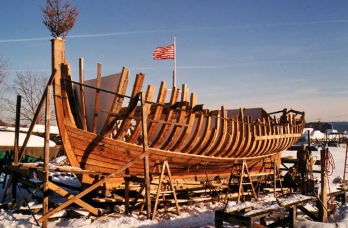 A large wooden boat is being built in the snow