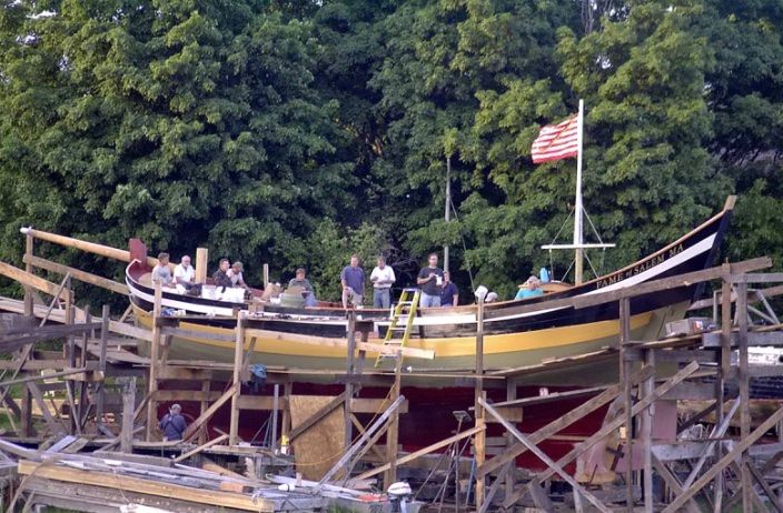 A group of people are standing on top of a boat being built