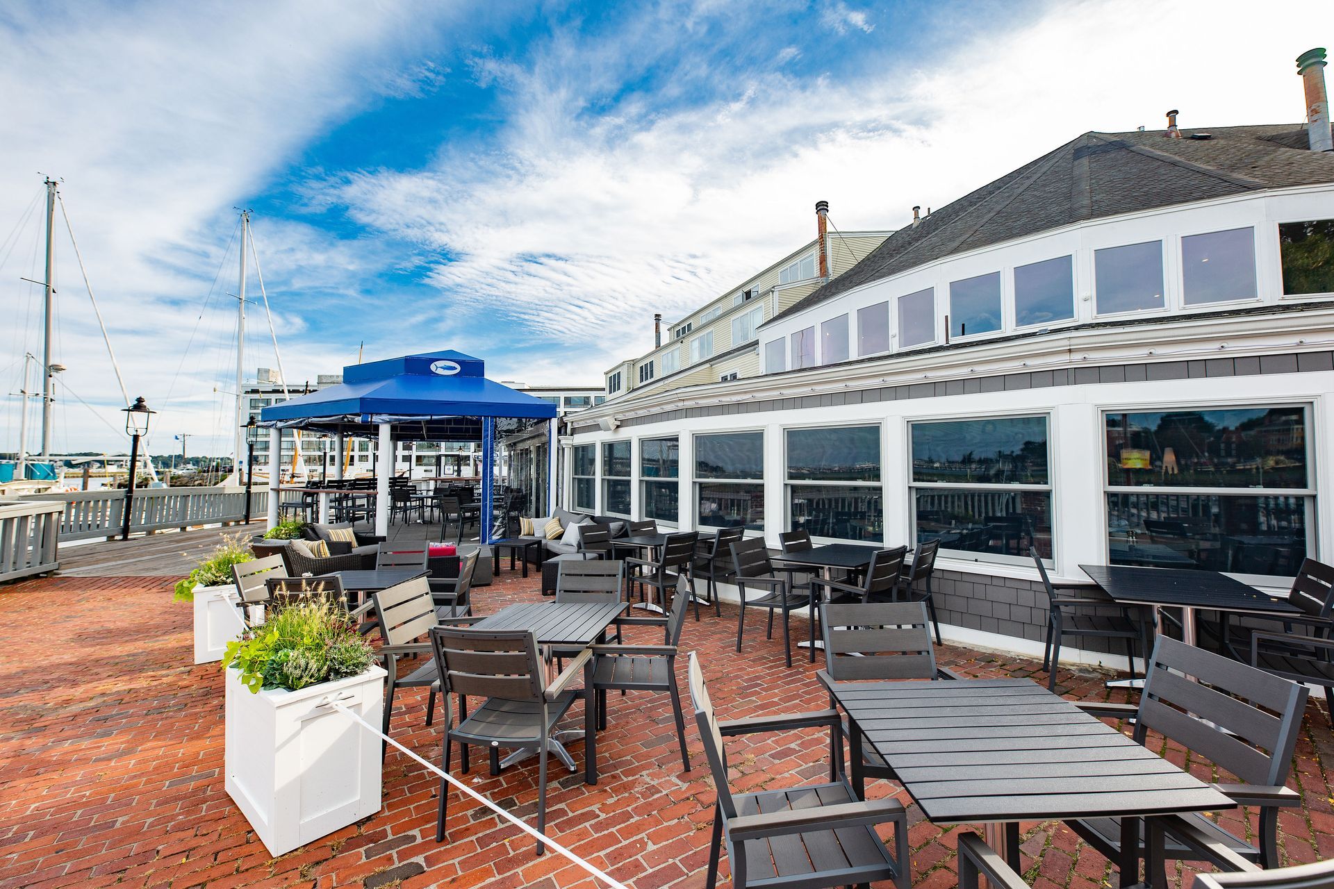 There are many tables and chairs on the patio of a restaurant.