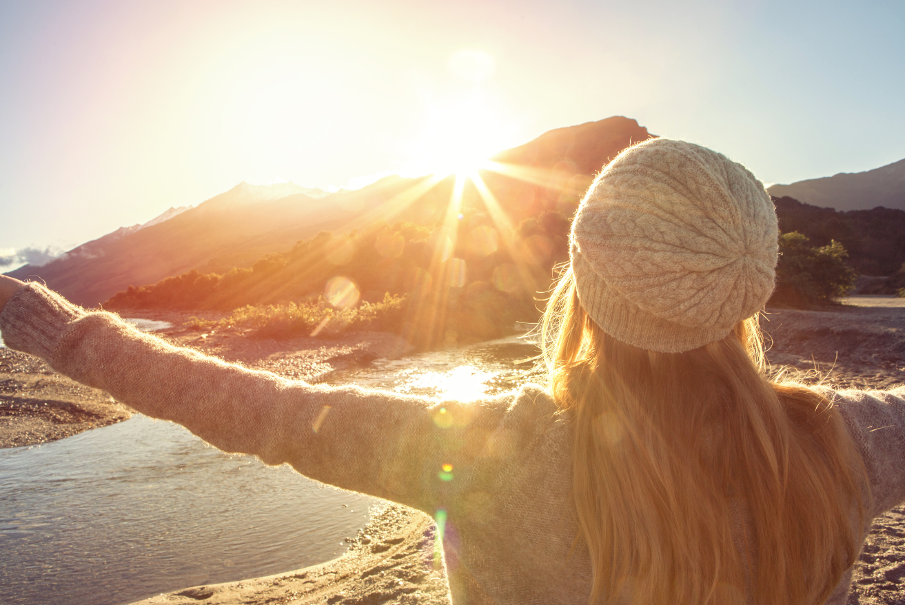 A woman in a green shirt is smiling with her eyes closed.