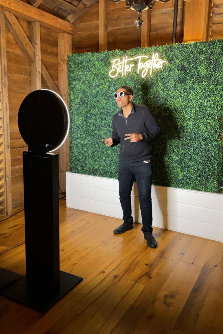 A man is standing in front of a photo booth in a room.