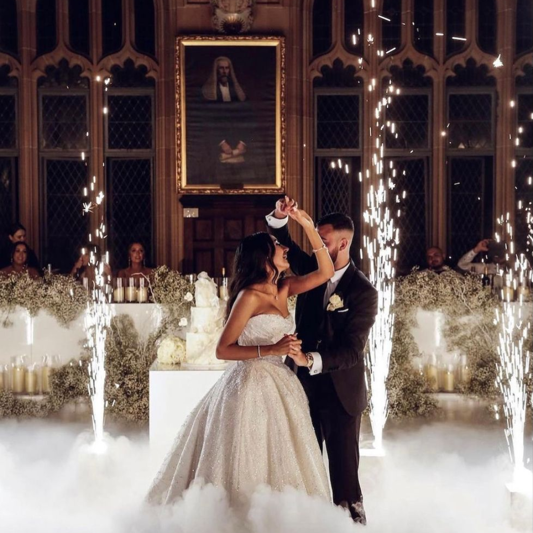 A bride and groom are dancing in front of sparklers