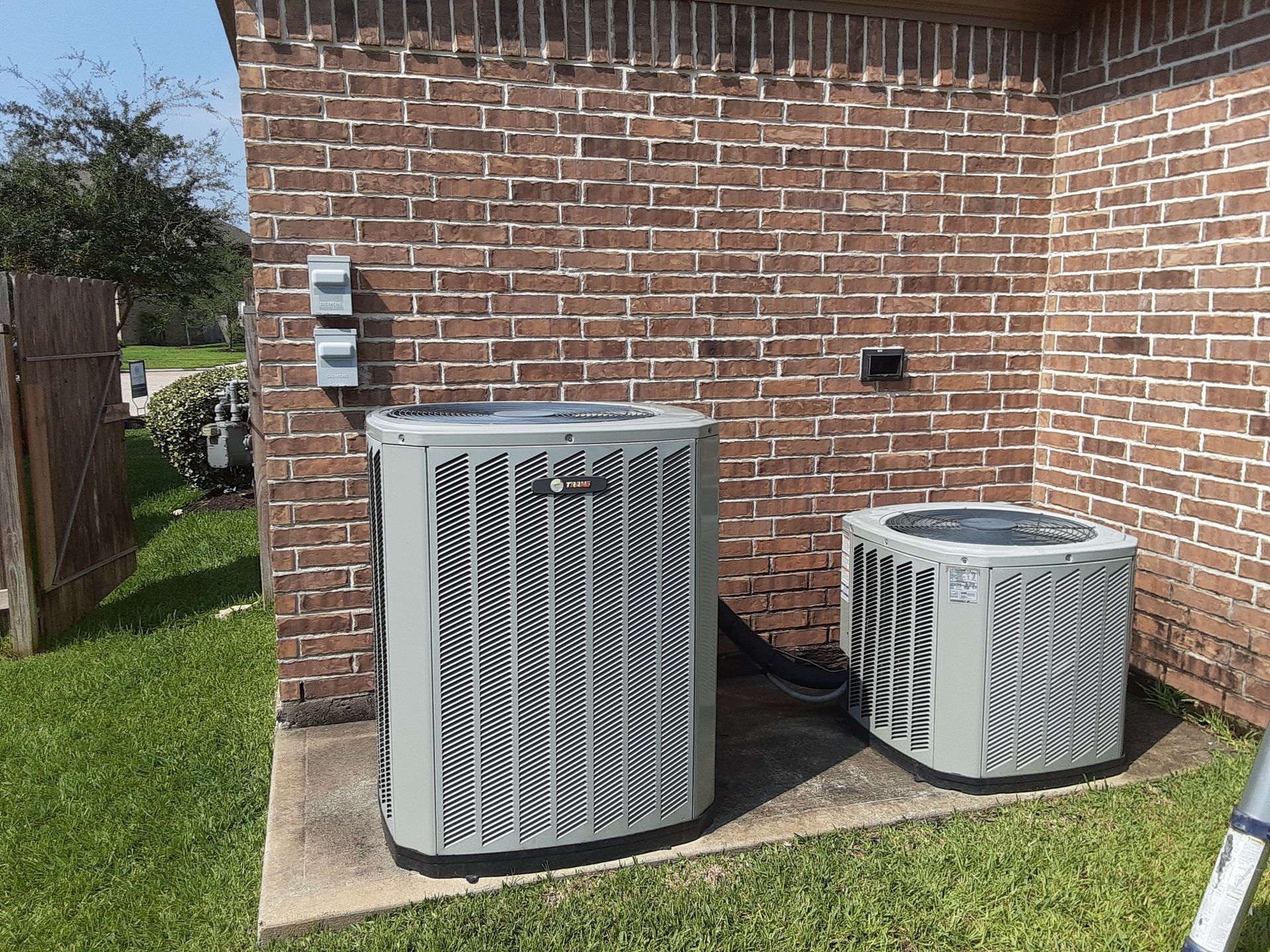 Outdoor AC units installed next to brick home by Arnett Mechanical in Rosharon TX