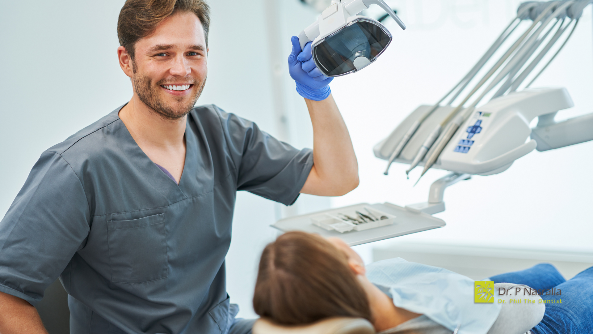 A dentist is holding a light over a patient in a dental chair.