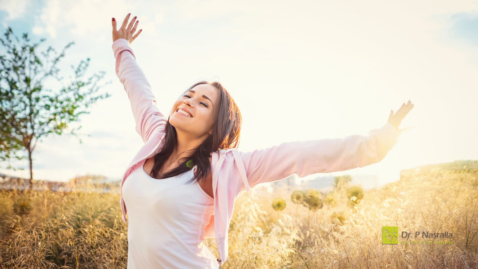 A woman is standing in a field with her arms outstretched.