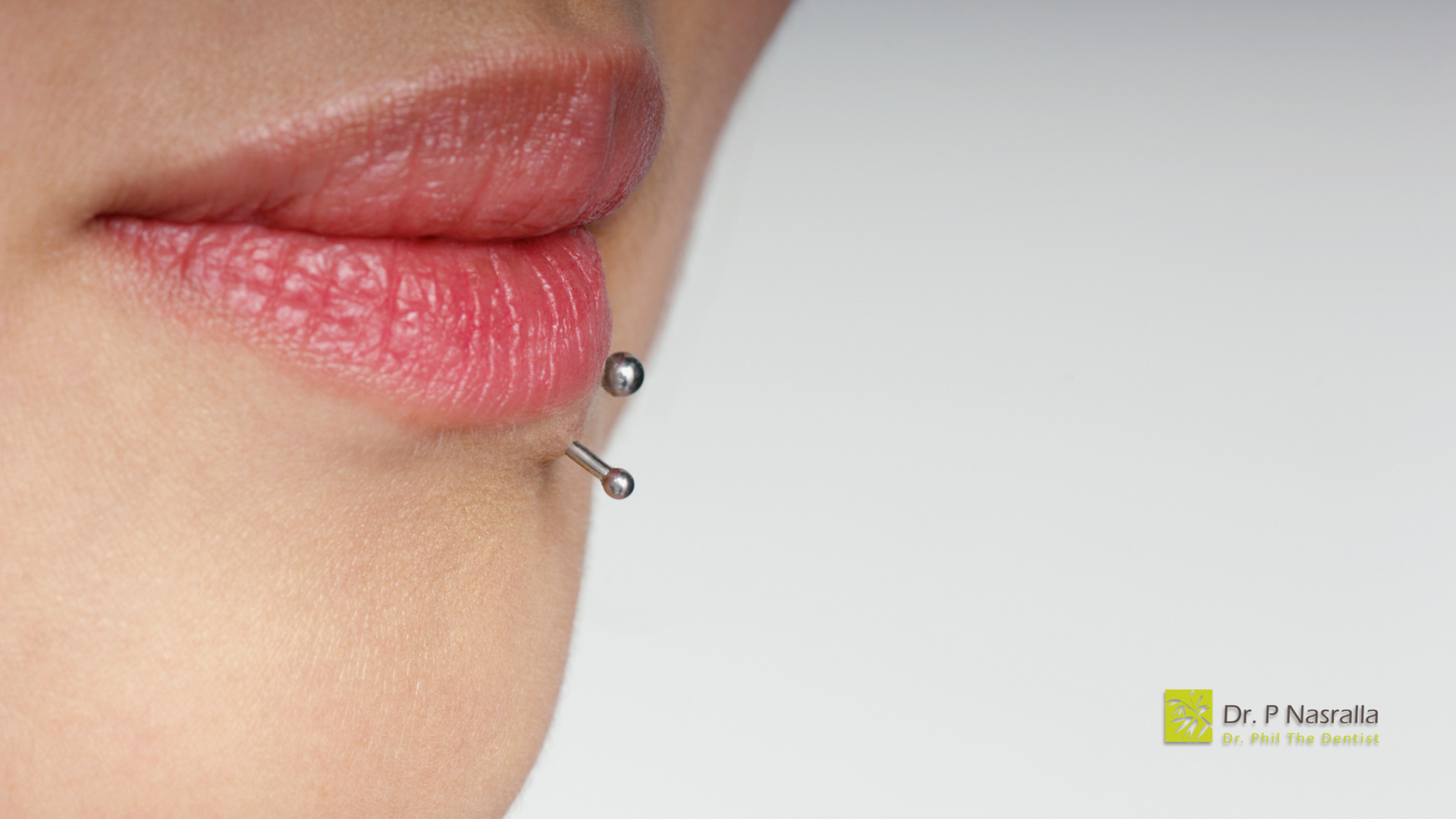 A close up of a woman 's lips with a lip piercing.