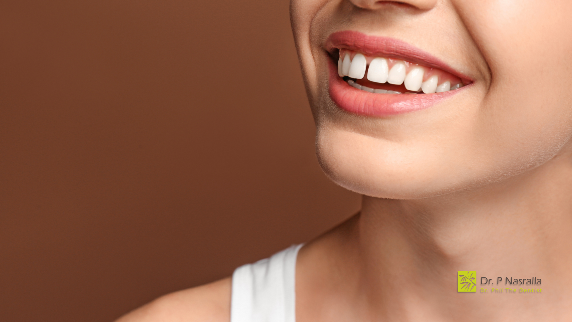 A close up of a woman 's smile with a brown background.