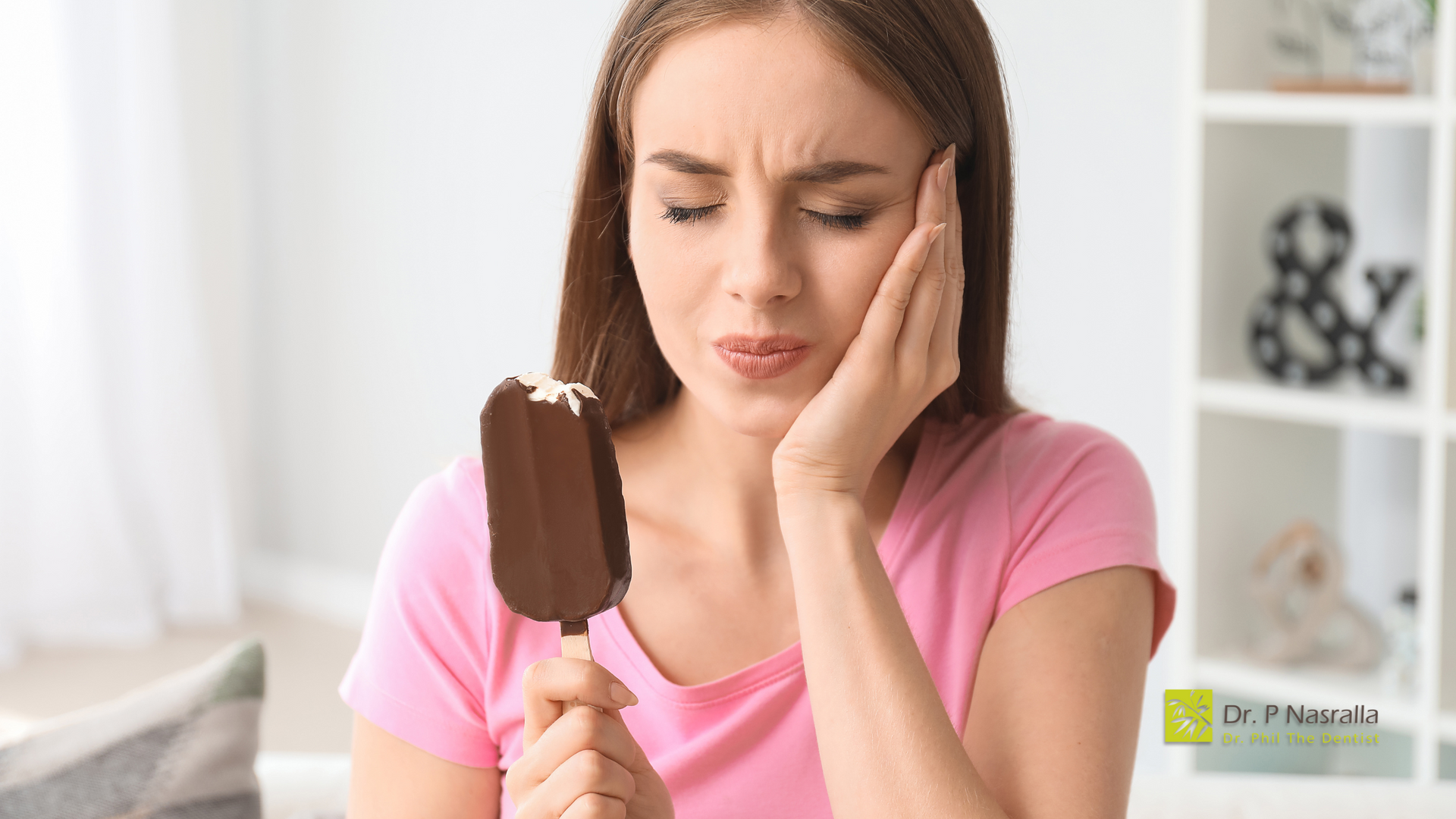 A woman is holding an ice cream bar with a bite taken out of it.