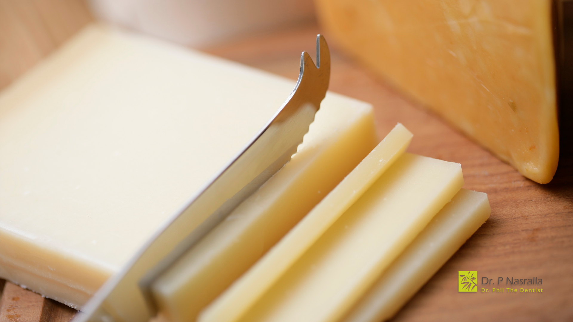 Cheese being sliced with a serrated knife on a wooden surface.