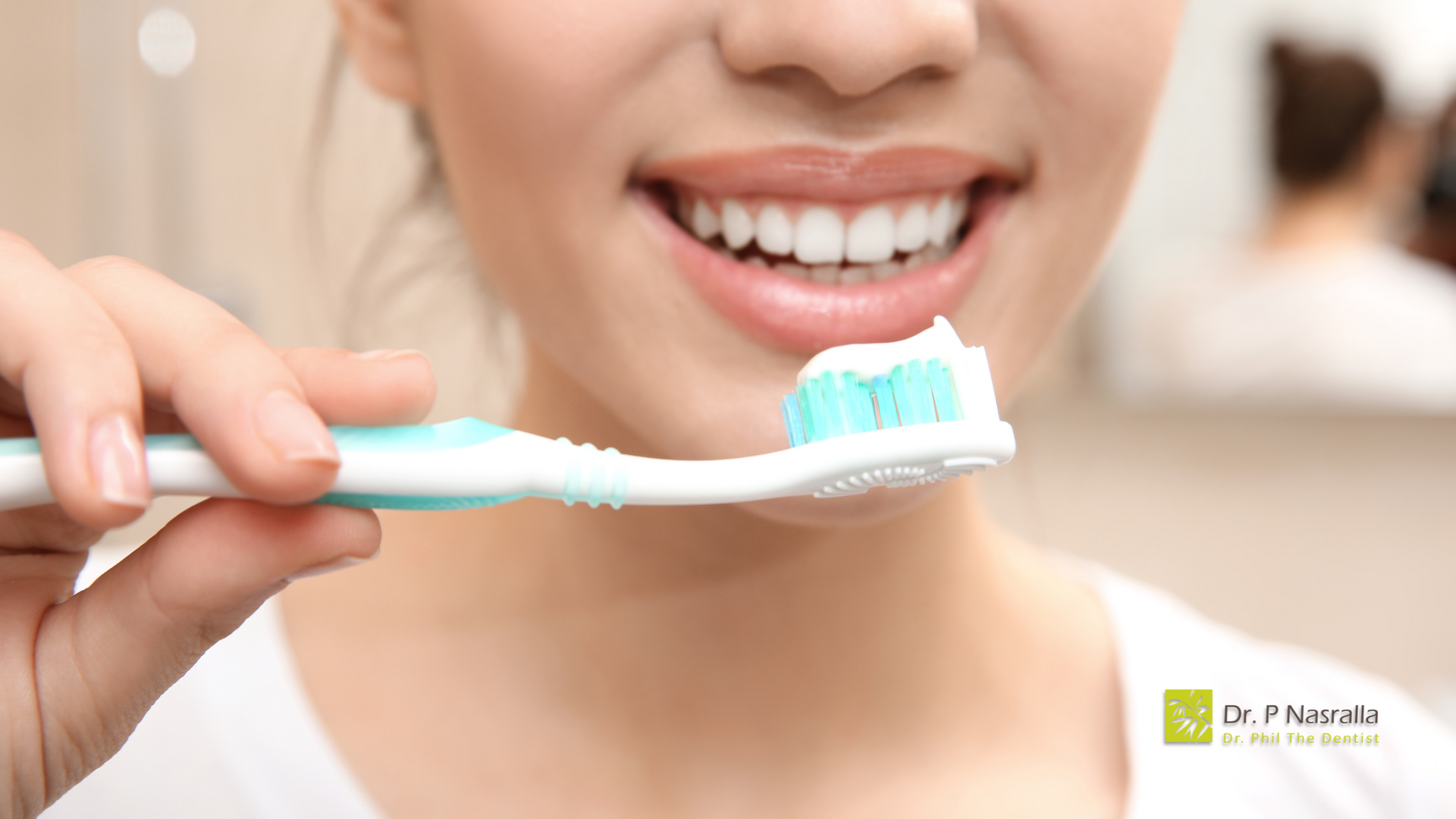 Woman smiling, holding a toothbrush with toothpaste, preparing to brush her teeth.