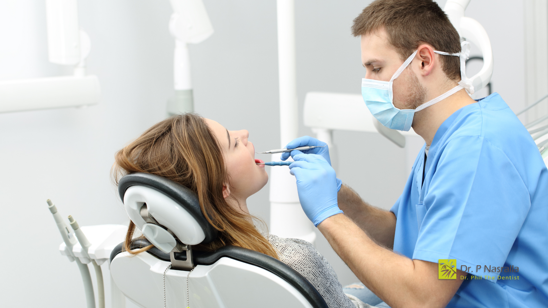 A woman is sitting in a dental chair while a dentist examines her teeth.