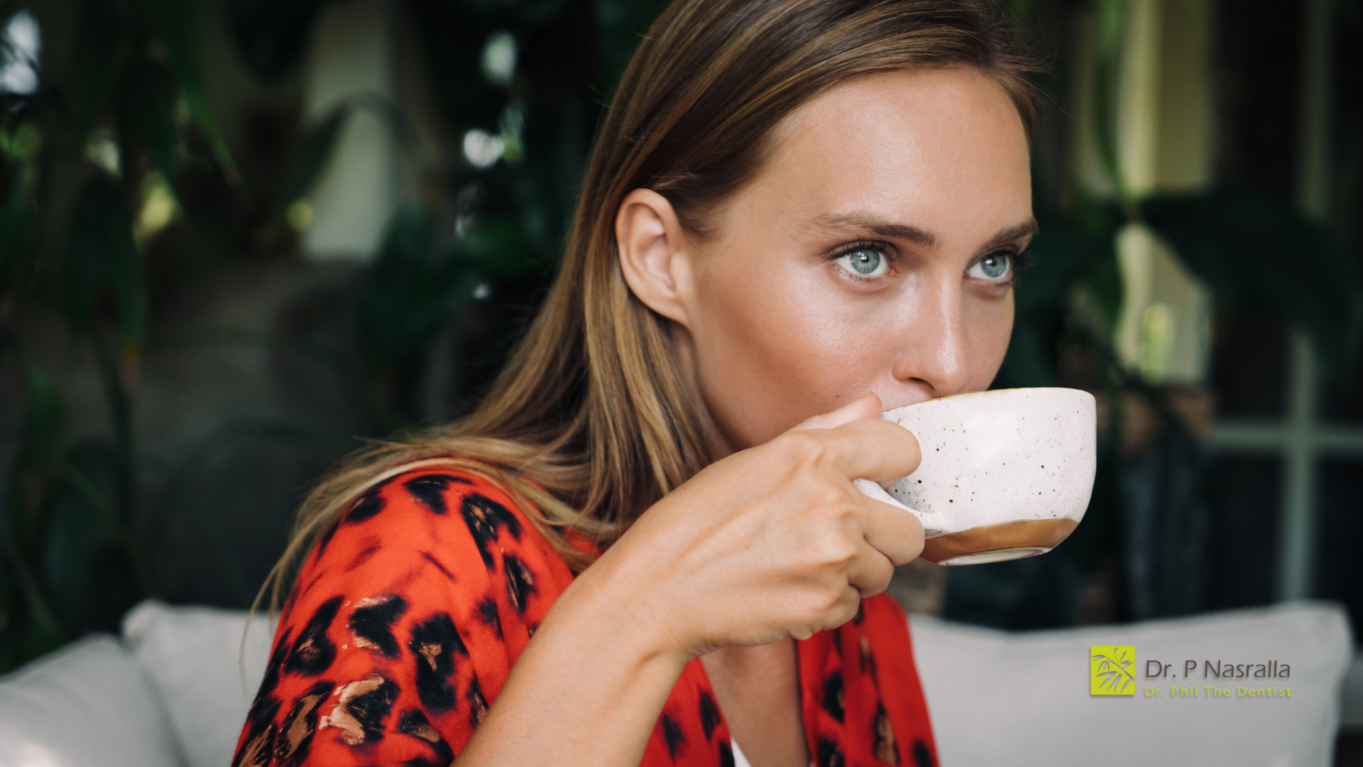 A woman is drinking a cup of coffee while sitting on a couch.