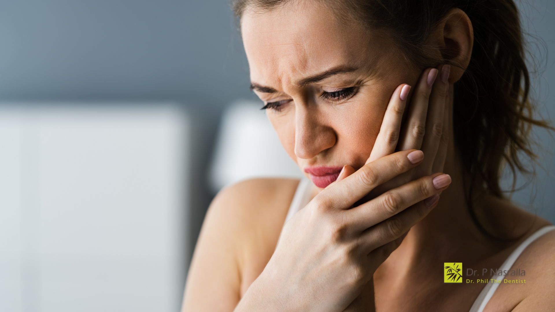 A woman is holding her face in pain because of a toothache.