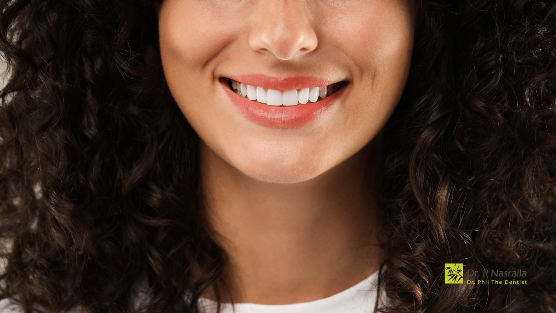 A close up of a woman 's face with curly hair smiling.