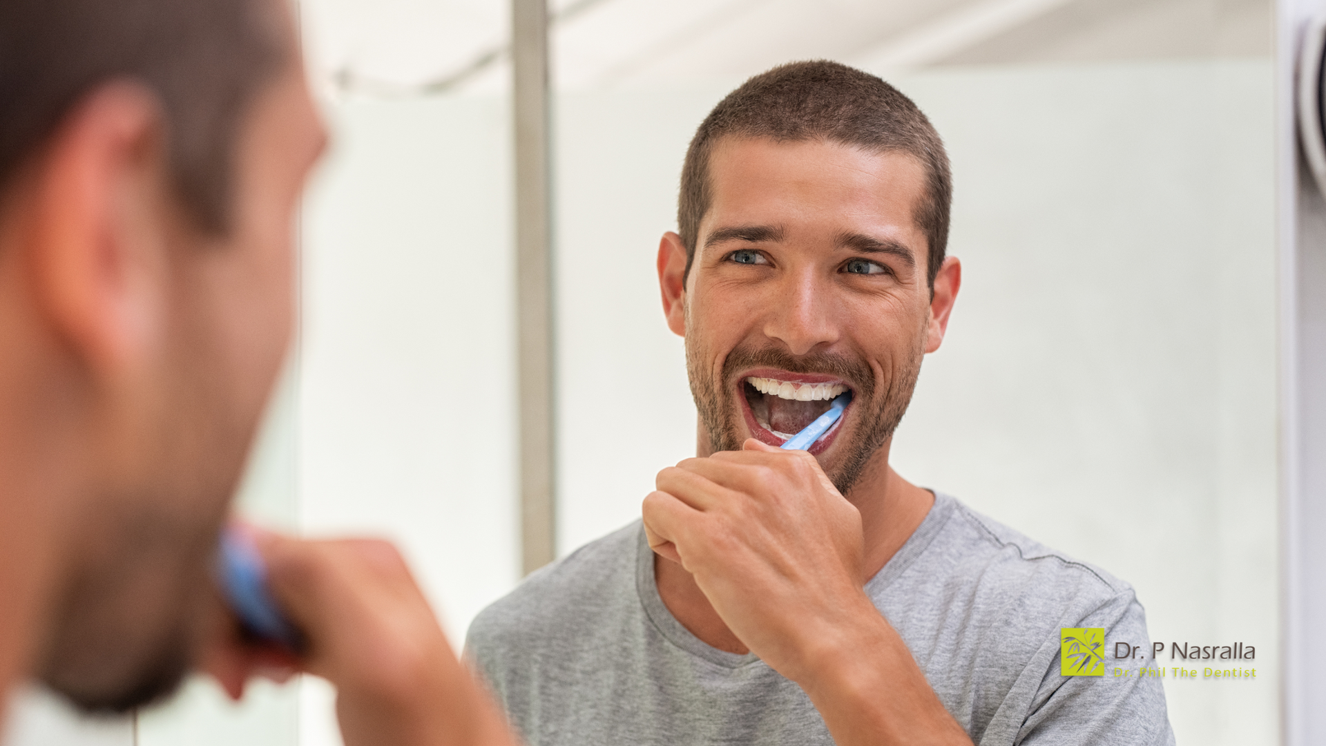 A man is brushing his teeth in front of a mirror.