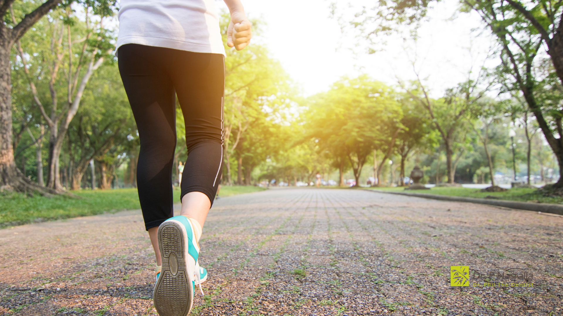 A woman is running down a path in a park.