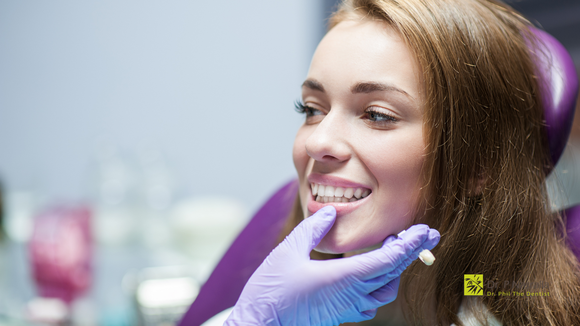 A woman is sitting in a dental chair while a dentist examines her teeth.