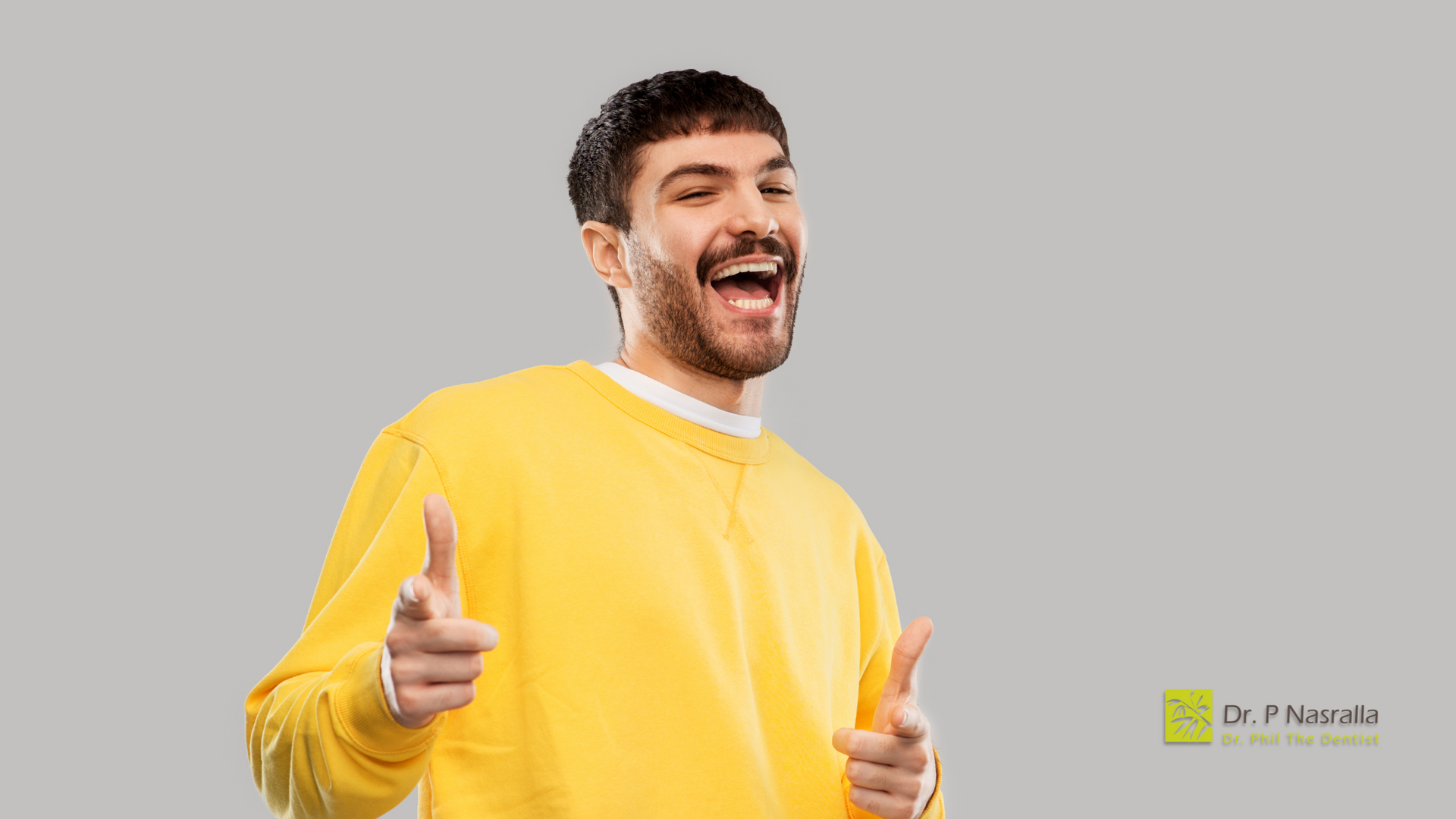 A man in a yellow sweater is giving two thumbs up.