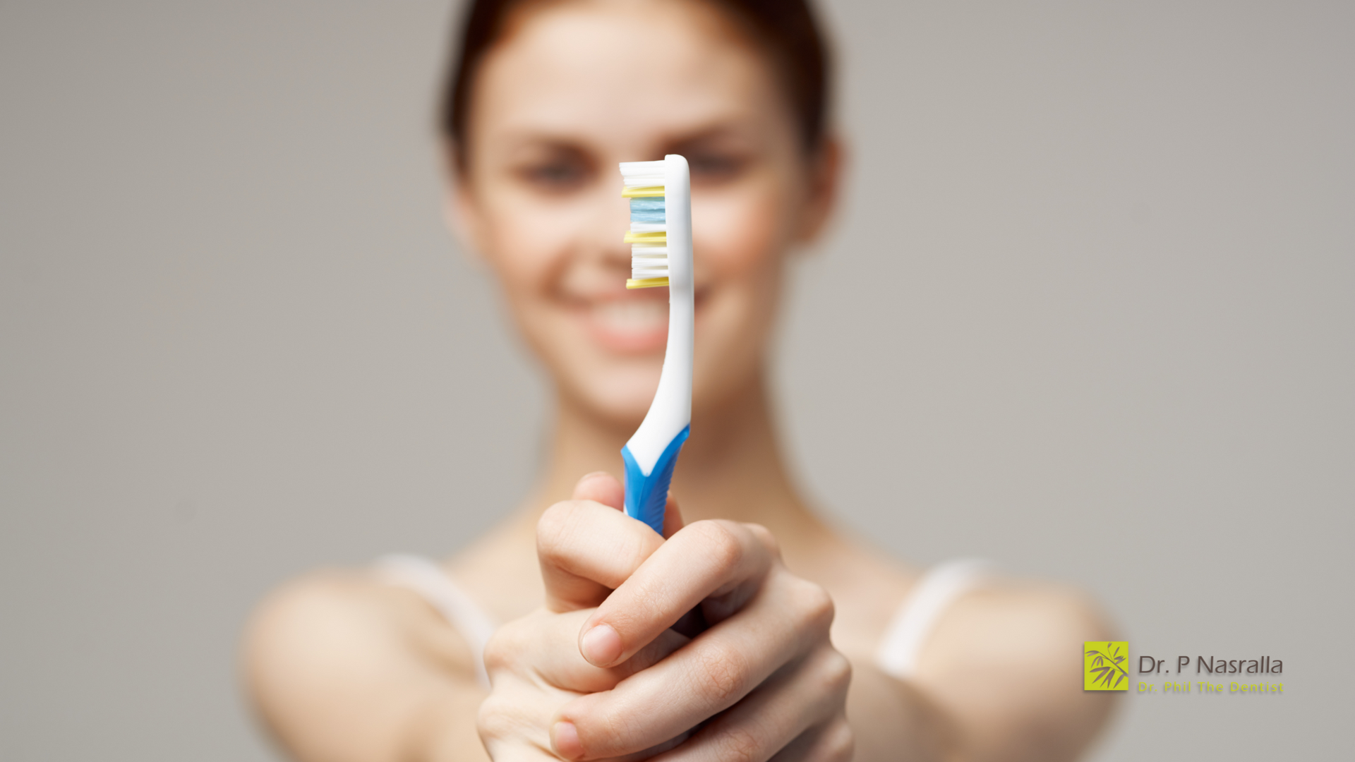 A woman is holding a toothbrush in her hand.