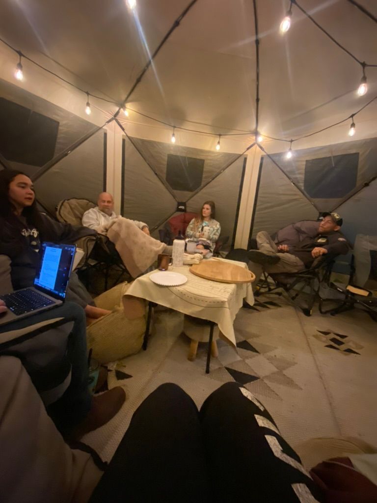 A group of people are sitting around a table in a tent.