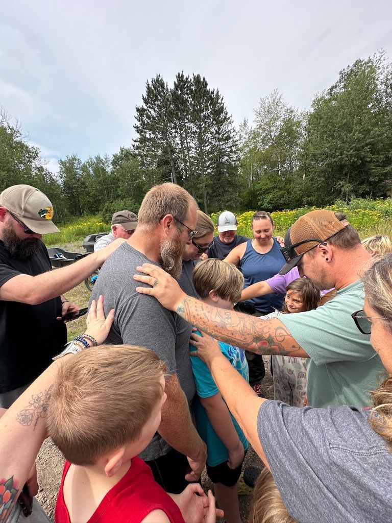 A group of people are standing in a circle with their hands on each other.