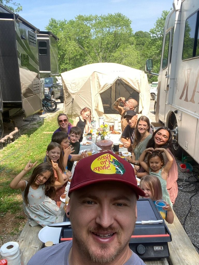 A man is taking a selfie with a group of people sitting at a table.