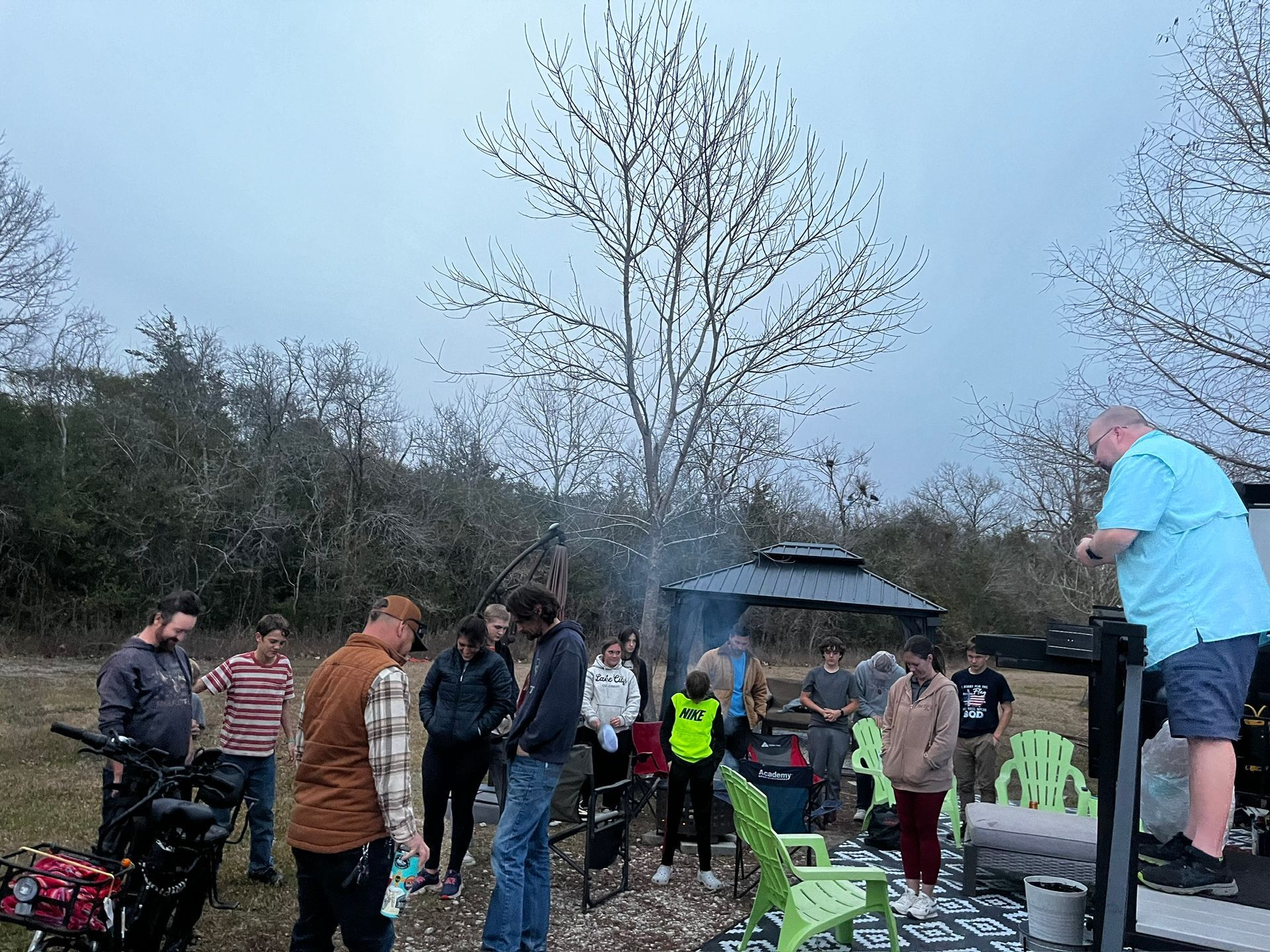 A group of people are standing around a fire pit.