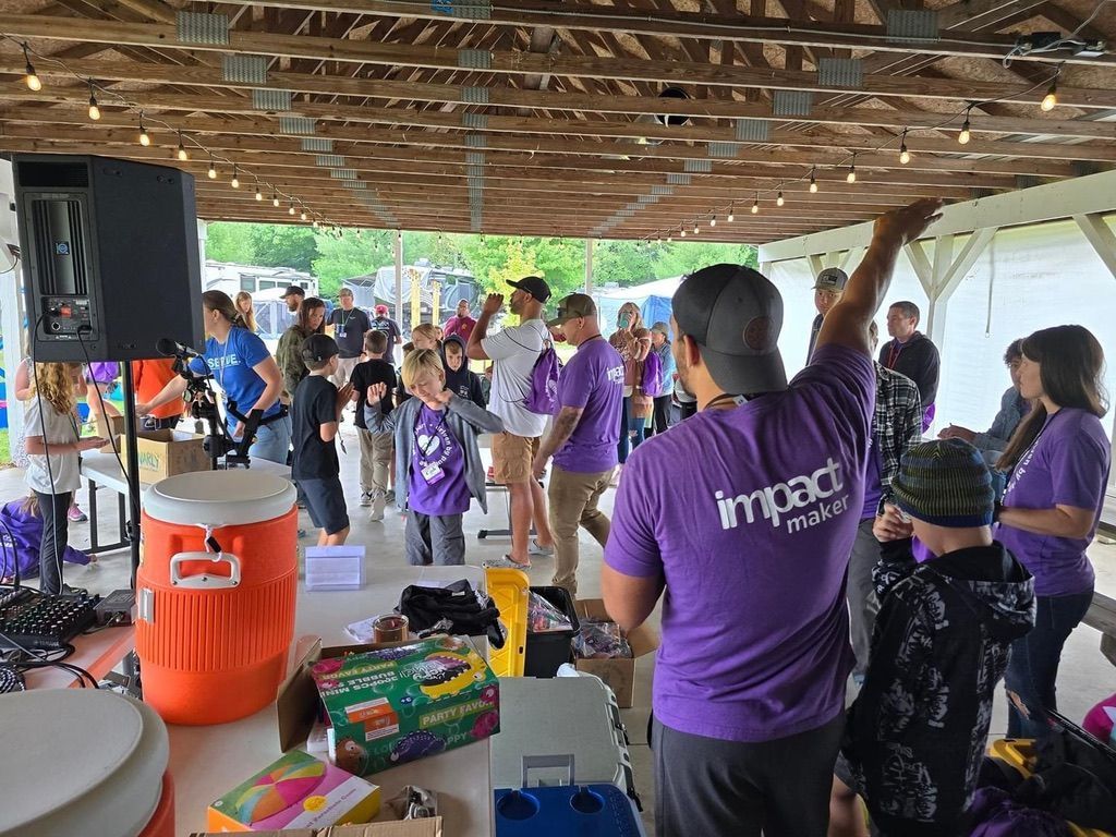 A group of people wearing purple shirts are standing under a covered area.