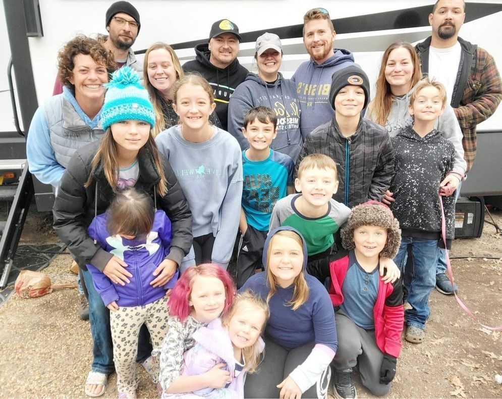 A group of people posing for a picture in front of a trailer.