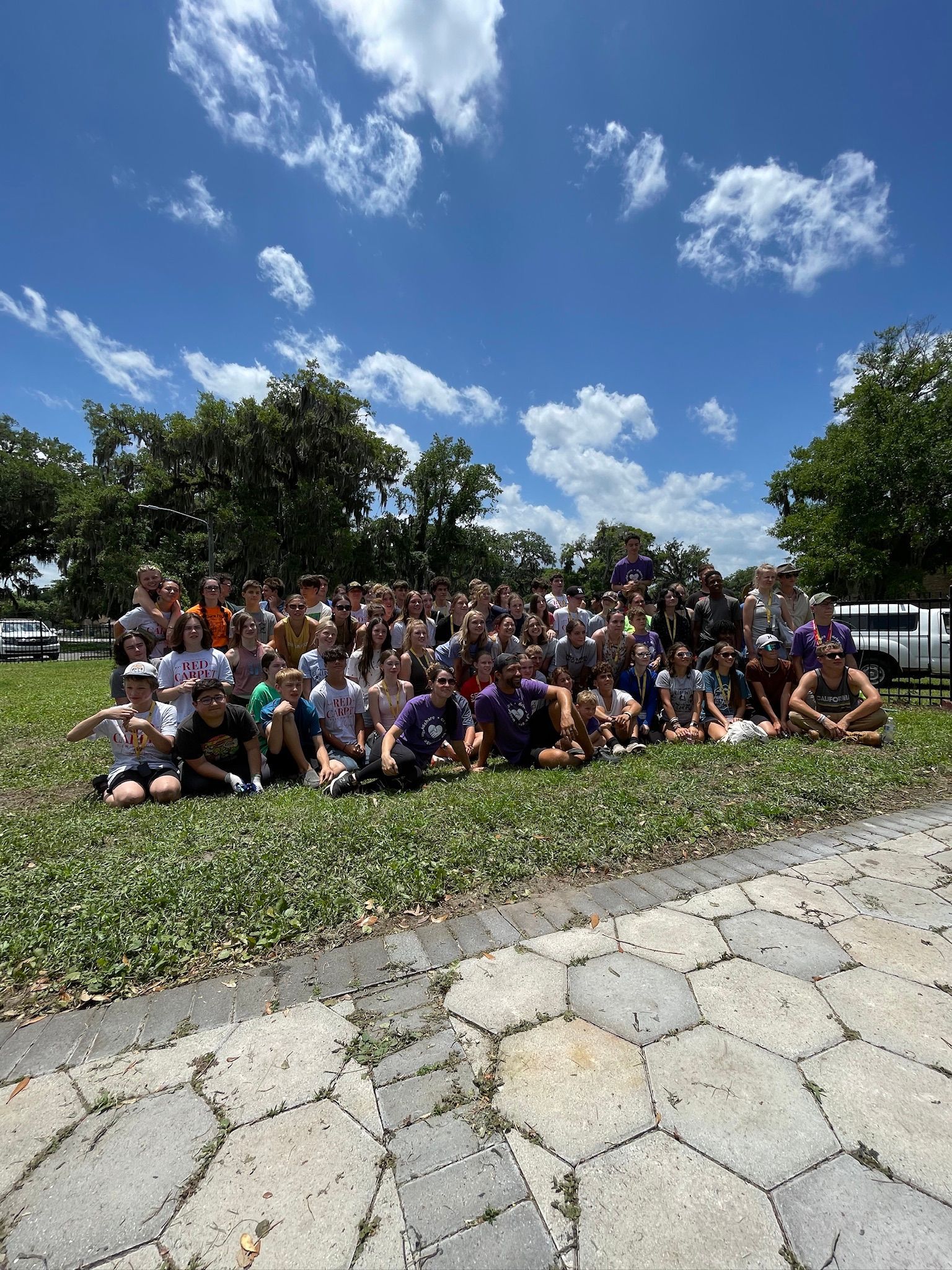 A large group of people are posing for a picture in a park.