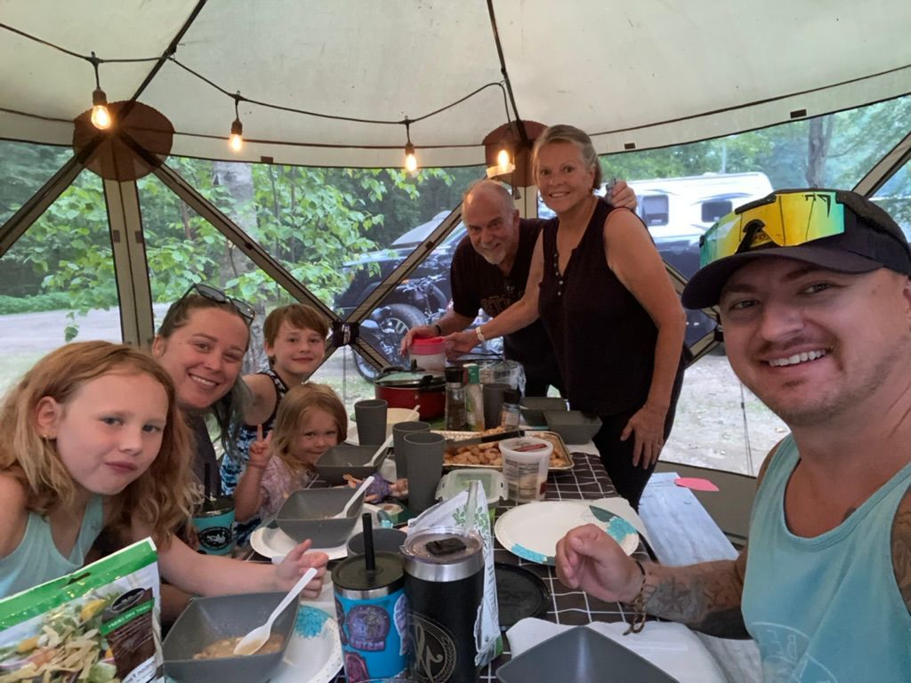 A group of people are sitting at a table in a tent eating food.