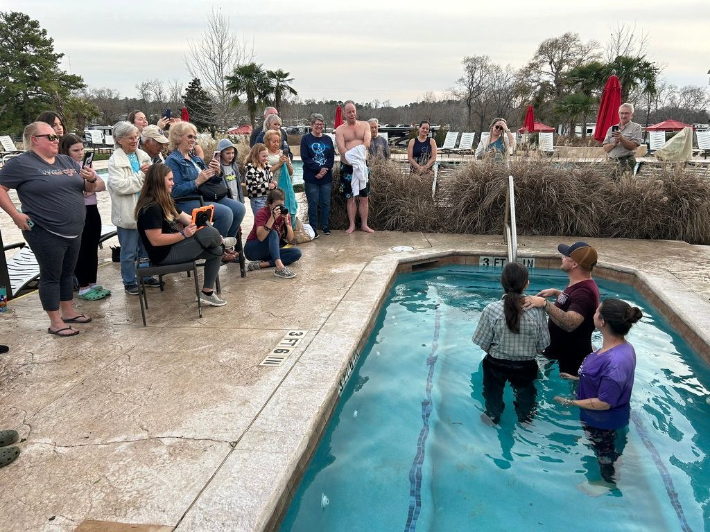A group of people are standing around a swimming pool.