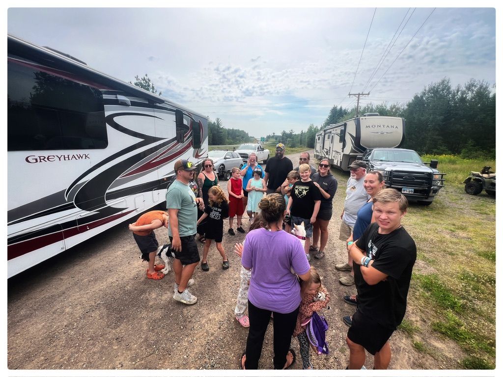 A group of people are standing in front of a rv.