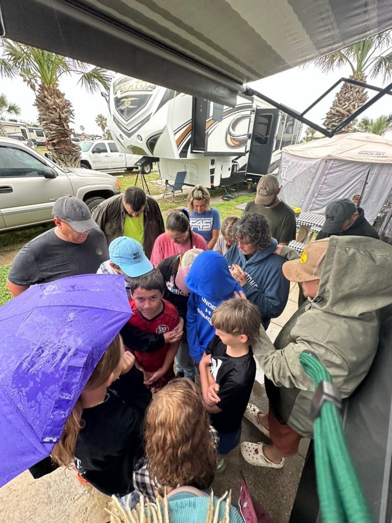 A group of people are standing around a trailer in the rain.