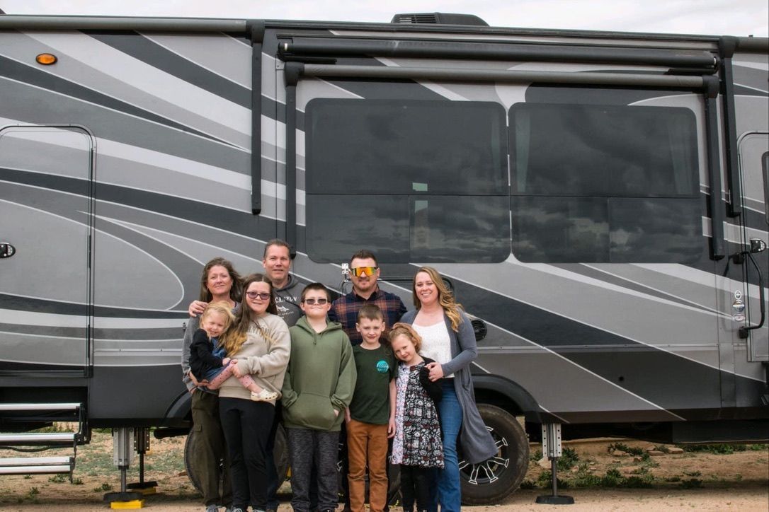 A family is posing for a picture in front of a rv.