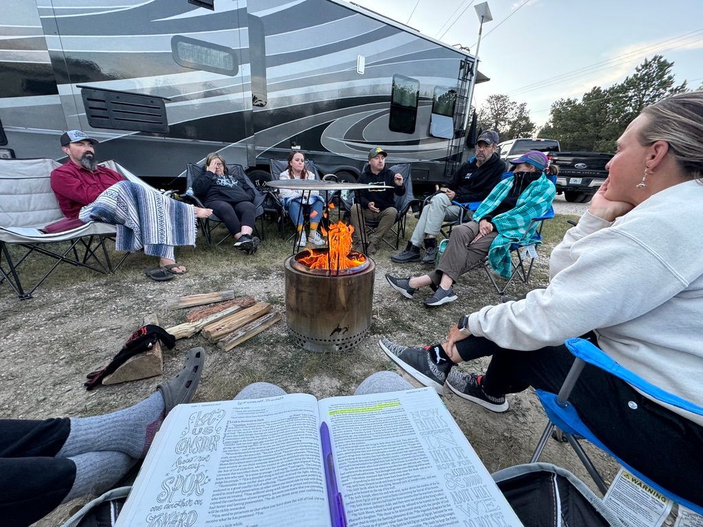 A group of people are sitting around a campfire.
