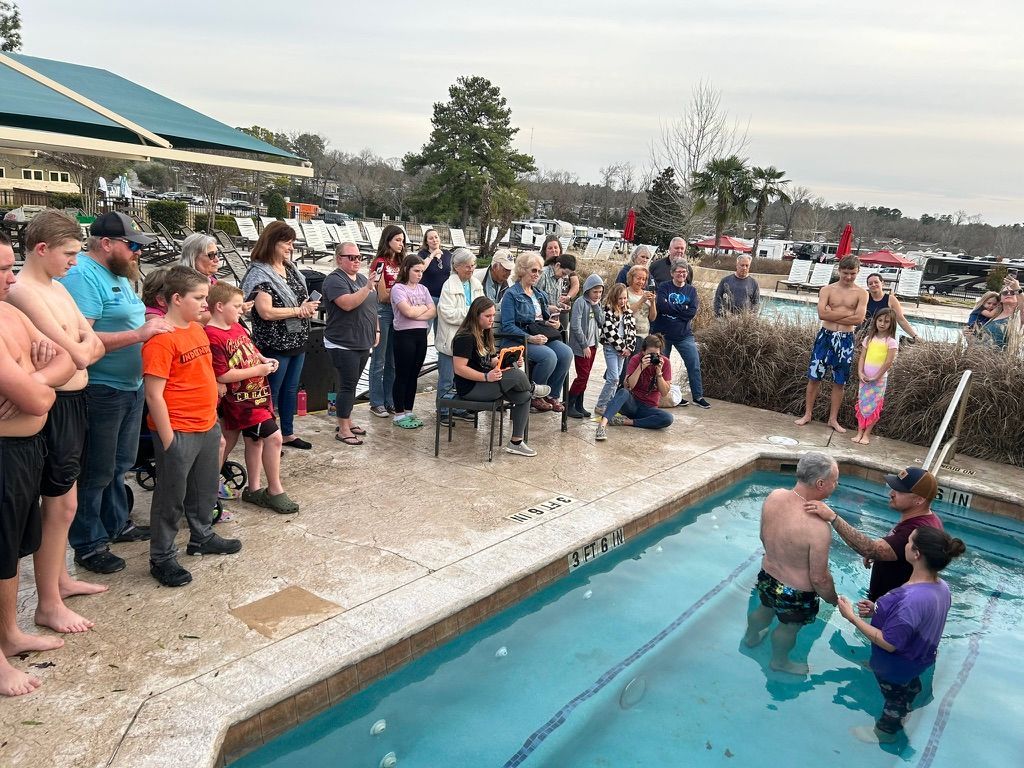 A group of people are standing around a swimming pool.