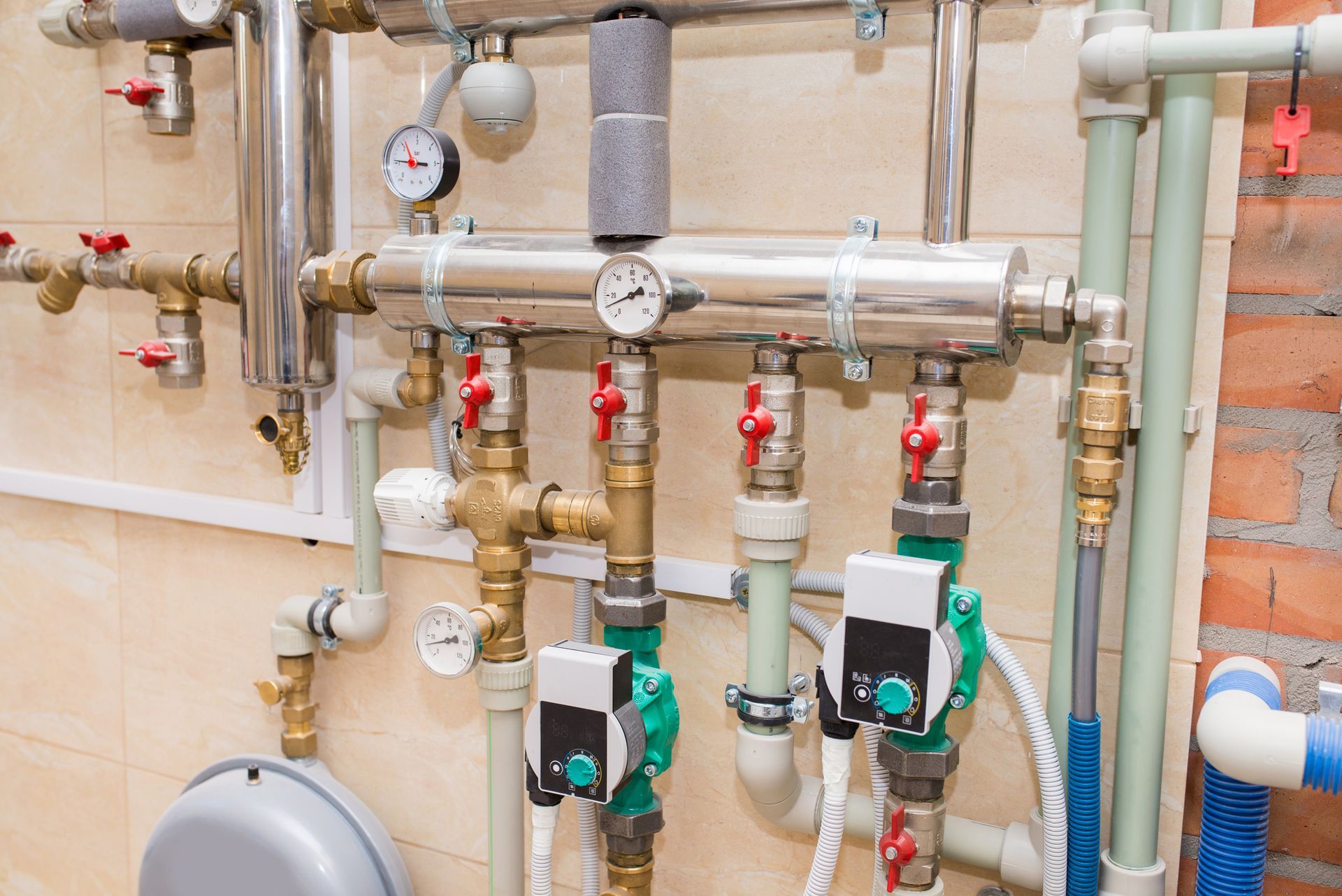 Tubazioni idrauliche con valvole, manometri e pompe in un ambiente interno. Vari materiali e colori.