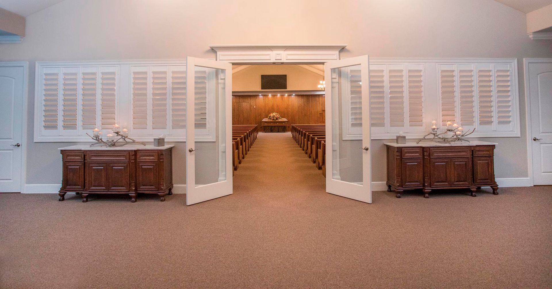 The doors are open to a church with a long aisle.