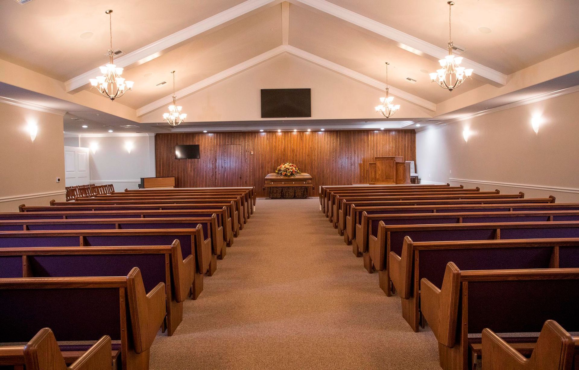 An empty church with purple benches and a wooden wall.
