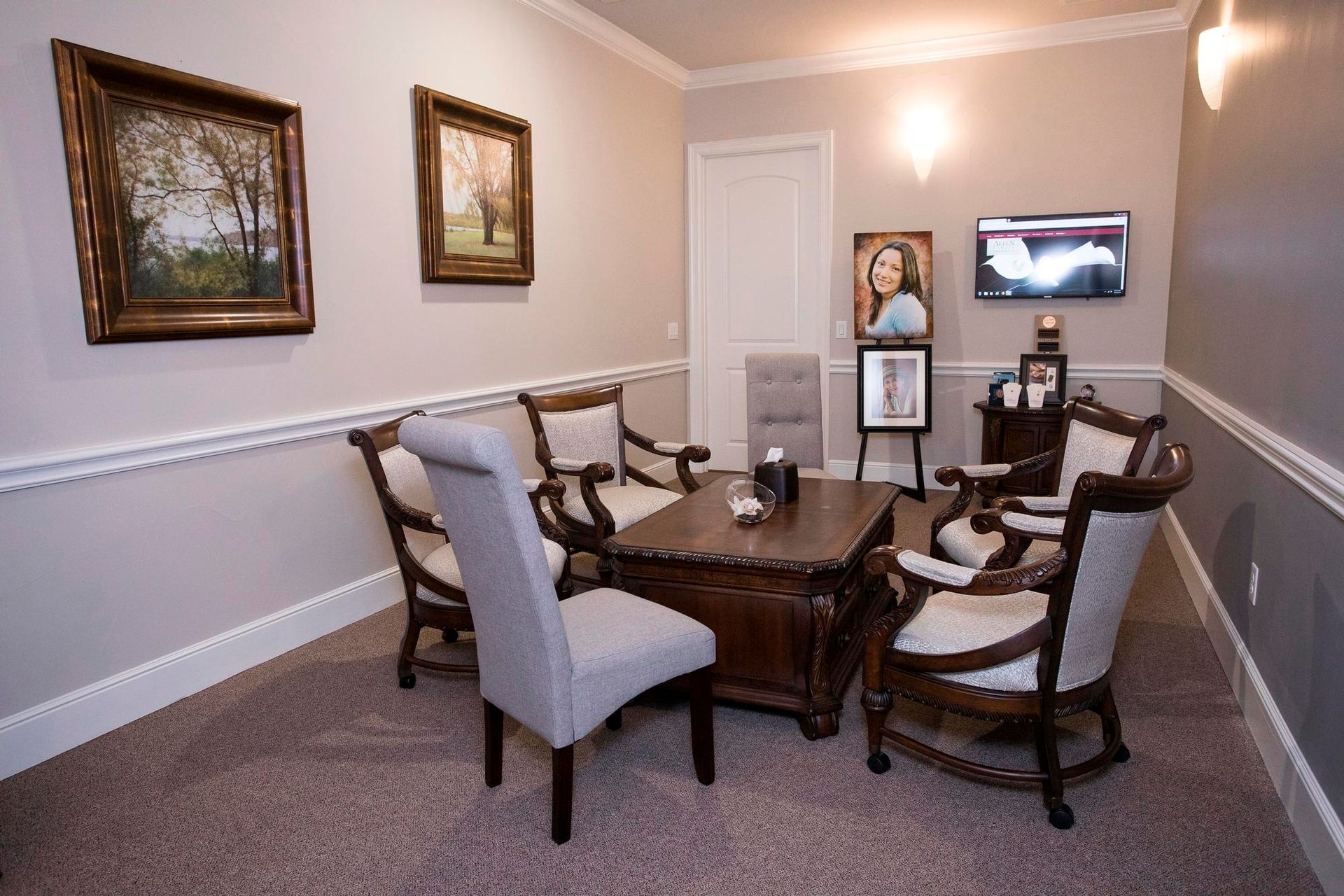 A living room with a table and chairs and paintings on the wall.